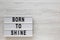 `Born to shine` words on a lightbox on a white wooden surface, top view. Overhead, from above, flat lay. Copy space