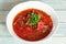 Borsch - beetroot soup in a white bowl on wooden background