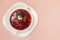 Borsch in white plate isolated on white. Beetroot soup on pink b