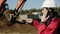 Boss of a builders in white helmet and red jacket is giving orders on his mobile phone.