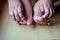 Both feet and hands on both sides of the boy on wooden floor