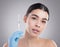 Botox beauty. Studio portrait of an attractive young woman holding a botox injection against a grey background.