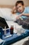 Bottle with antipyretic syrup, nasal spray and thermometer on napkin. Little boy in bed in foreground out of focus