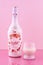 A bottle of Baileys with glass. Strawberries and cream. Limited edition. Liquor on a pink background. Alcohol drink. Illustrative