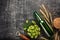 A bottle of beer with a green hops, spikelets, bowl oats and opener on a black scratched chalk board