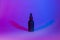 A bottle of black matte color on a neon trend background. Cosmetics concept. Minimum