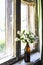 A bottle with blooming jasmine branches by the window in a rustic house