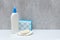 a bottle of body care gel, soap in a soap dish and a sponge. Gray background