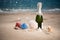 Bottle of champagne on the beach with a gift boxes and shells