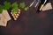 Bottle of champagne, gape bunch of cork with leaves, two wineglass and envelope on rusty background.