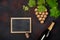 Bottle of champagne, grape bunch of cork with leaves and chalkboard on rusty background