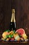 A bottle of champagne, pears, vivid grapefruit, lime, fresh green leaves of mint, blueberry on a wooden background.