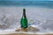A bottle of champagne with a poured glass is standing on the seashore