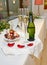 Bottle of champagne, two glasses and chocolate strawberries on a tray with rose petals