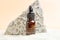 Bottle of cosmetic product serum oil and stone podium with beach white sand. Abstract podium product presentation sandy background