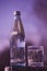 A bottle of drinking water and glass stands against the background of a violet