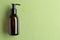 Bottle and drops of hydrophilic oil on light green background, flat lay. Space for text