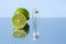 A bottle of essential natural oil and fresh lime fruit on a blue background. Citrus scent. The concept of natural cosmetics for