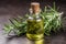 Bottle of essential oil with fresh rosemary twigs on wooden table. Rosemary oil for hair growth in a small bottle surrounded with