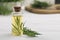 Bottle of essential oil and fresh tarragon leaves on white wooden table. Space for text