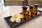 Bottle of essential oil and jasmin flower with plumeria flower setup on marble table.