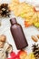 Bottle of essential oil on white table with autumn leaves and pine cones, spa concept