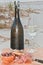 Bottle and glass of champagne, with sliced salami, knife, French bread, rare wood bowl of black olives,