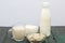 Bottle and glass with milk. Next to granola and soft cheese in a container. On brushed pine boards