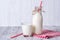 Bottle and glass of milk with red straw, wooden background