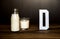 Bottle and glass of milk with a white letter D. Products containing vitamin D