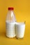 Bottle and glass with milk on a yellow background.