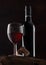 Bottle and glass of red wine with corks and vintage corkscrew on top of wooden barrel on black