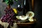 Bottle and glass of red wine, grape and cork on chair. Melon, piece of melon. Pink grape, pear. Still life of food. Dark