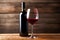 Bottle and a glass of red wine on rustic wooden background, wine tasting and winery, post-processed, generative ai