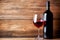 Bottle and a glass of red wine on rustic wooden background, wine tasting and winery, post-processed, generative ai