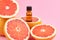 Bottle of grapefruit essential oil on fresh grapefruit background. Aromatherapy treatment. Naturopathic medicine