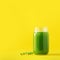 Bottle of green celery smoothie on yellow background. Banner with copy space. Square crop. Fresh juice for detox. Vegan, alkaline