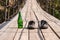 A bottle of green glass on a wooden bridge next to old worn shoes