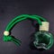 bottle of green home fragrance perfume with hanging thread and wooden cap on dark black background