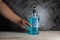 bottle of hand sanitizer blue gel with ingredient ethyl alcohol 95% in hand human on wooden table with dark background