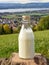 Bottle of homemade village milk against the backdrop of the village. AI