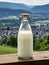 Bottle of homemade village milk against the backdrop of the village. AI