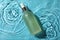 Bottle of hydrophilic oil in water on light blue background, top view