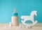 Bottle with infant formula milk near rocker horse toy and sugar