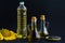 Bottle and jug of refined and unrefined sunflower oil, yellow flower and seeds on dark black background