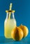 Bottle with lemon juice, natural lemons, blue background