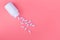 Bottle of medicines and scattered pills on a pastel pink background. Ripped vitamins on a bright background