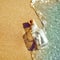 A bottle with a message is thrown by a wave on a sandy beach. Concept of hope The bottle floats in the surf line