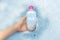A bottle of micellar water floating in soapy water. Harmful composition of ingredients. Cleanser with SLS. The concept of
