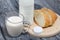 Bottle of milk, a glass of fermented baked milk and slices of ciabatta bread on a cutting board. On brushed pine boards